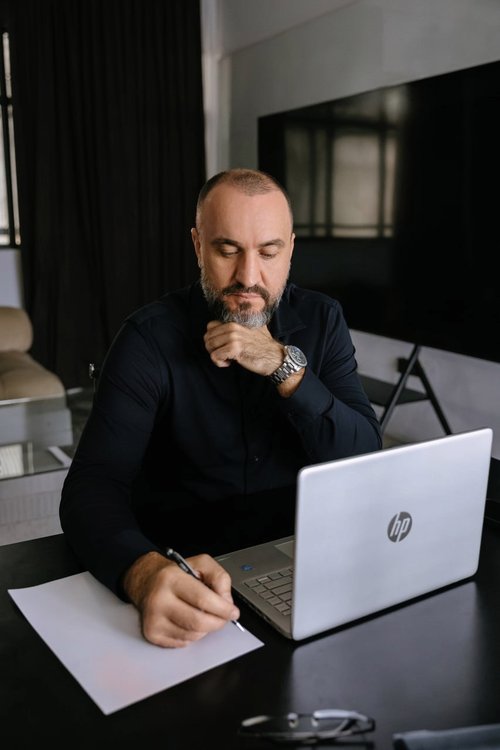 Денис Бачинин — за ноутбуком HP, с ручкой над листом бумаги